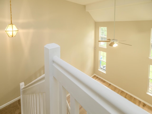 interior space featuring an upstairs landing, baseboards, wood finished floors, and lofted ceiling with beams