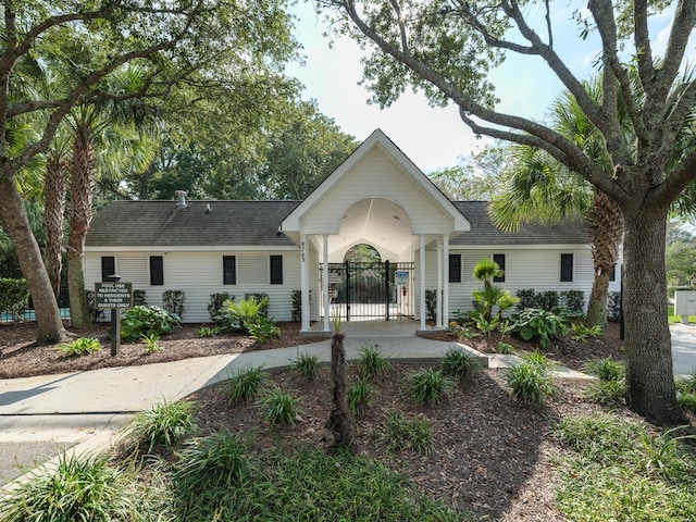 ranch-style home featuring roof with shingles and a gate