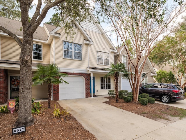 multi unit property featuring brick siding, driveway, and an attached garage