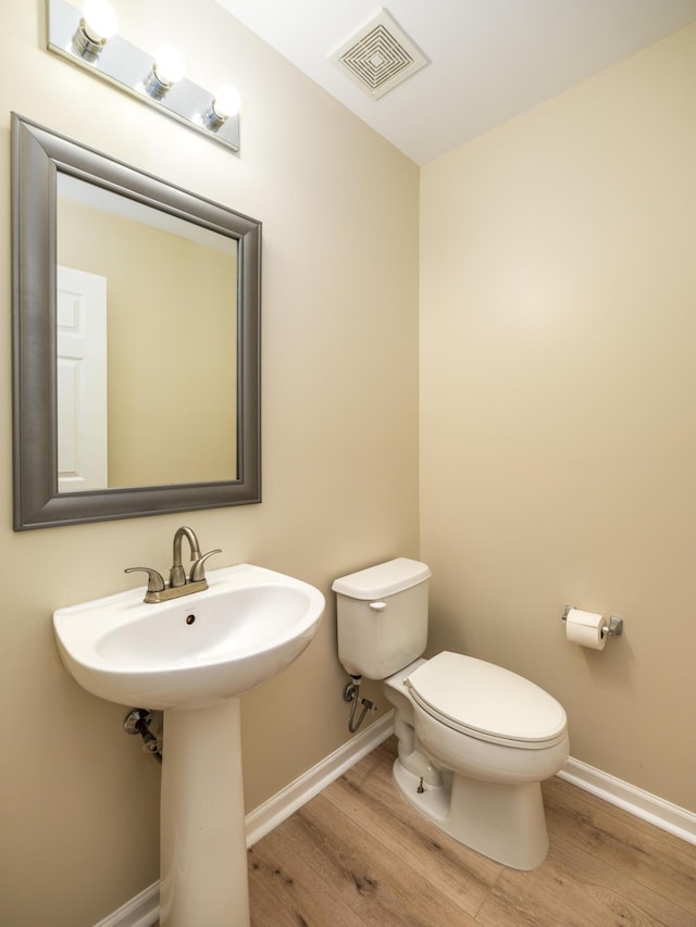 bathroom featuring toilet, wood finished floors, baseboards, and visible vents