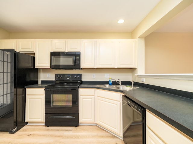 kitchen with a sink, light wood-type flooring, dark countertops, recessed lighting, and black appliances