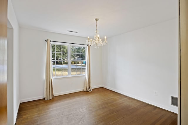 empty room featuring wood-type flooring and a chandelier