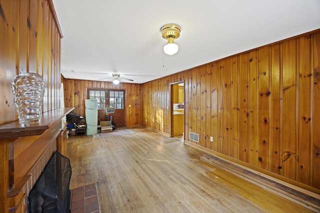 interior space featuring ceiling fan, hardwood / wood-style floors, and wood walls