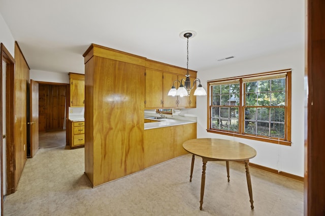 kitchen featuring pendant lighting, an inviting chandelier, and kitchen peninsula