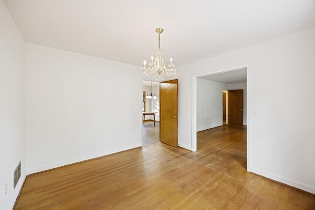 unfurnished room with wood-type flooring and an inviting chandelier