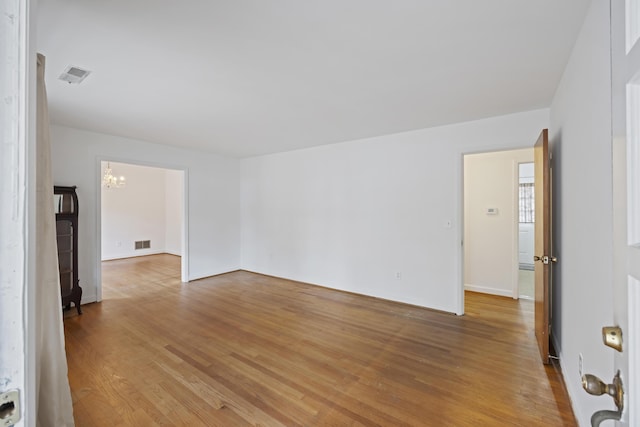 unfurnished room with an inviting chandelier and light hardwood / wood-style flooring