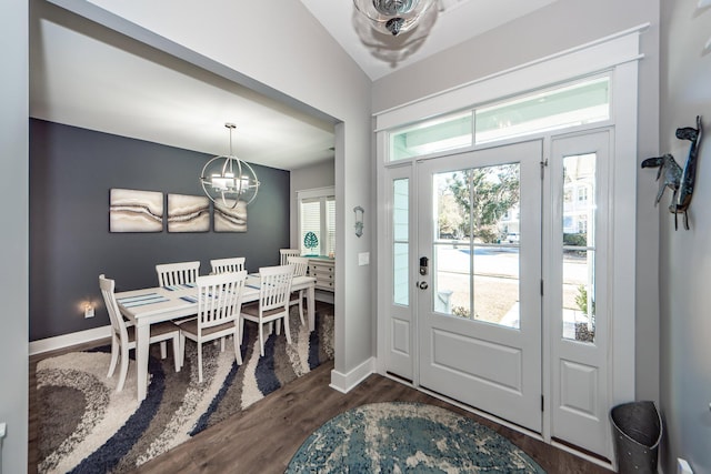 foyer entrance with vaulted ceiling, dark hardwood / wood-style floors, and an inviting chandelier