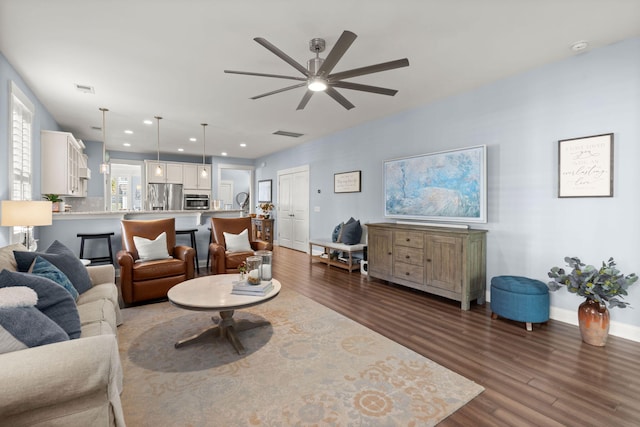 living room featuring ceiling fan and dark wood-type flooring