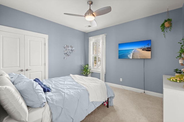 bedroom with ceiling fan, light carpet, and a closet