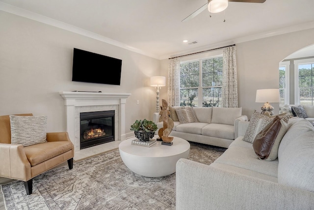 living room with ornamental molding, ceiling fan, and a high end fireplace