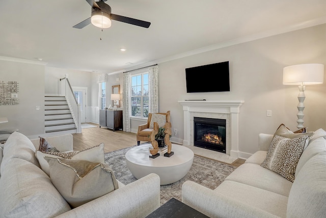 living room with crown molding, light hardwood / wood-style floors, and ceiling fan