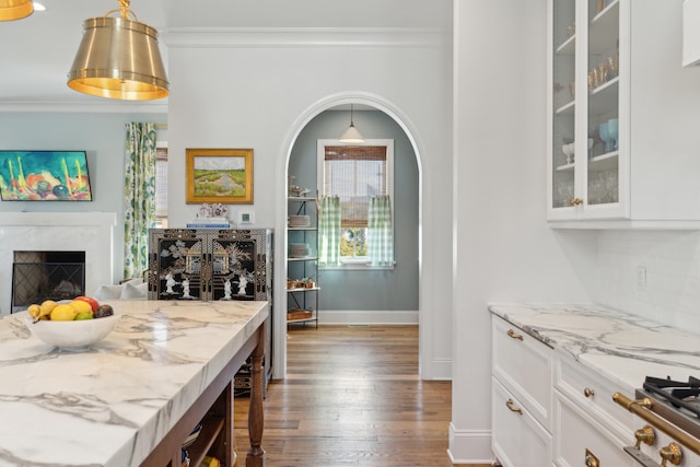 bar with a premium fireplace, white cabinetry, and light stone countertops