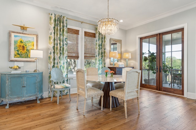 dining space with wood-type flooring, ornamental molding, and an inviting chandelier