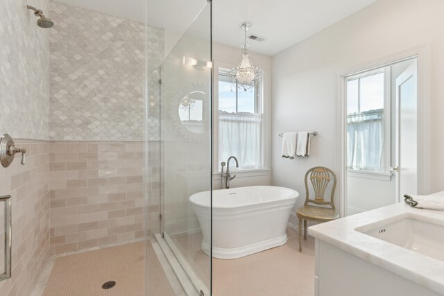 bathroom featuring vanity, an inviting chandelier, a wealth of natural light, and independent shower and bath