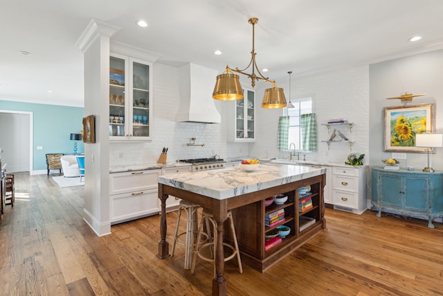 kitchen featuring premium range hood, white cabinets, light wood-type flooring, and a kitchen island