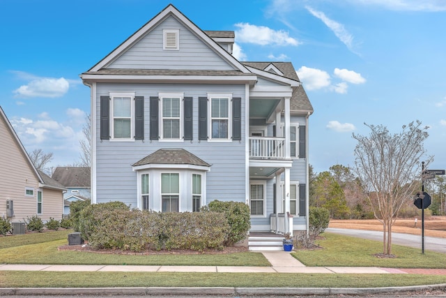 view of front of house featuring cooling unit, a balcony, and a front yard