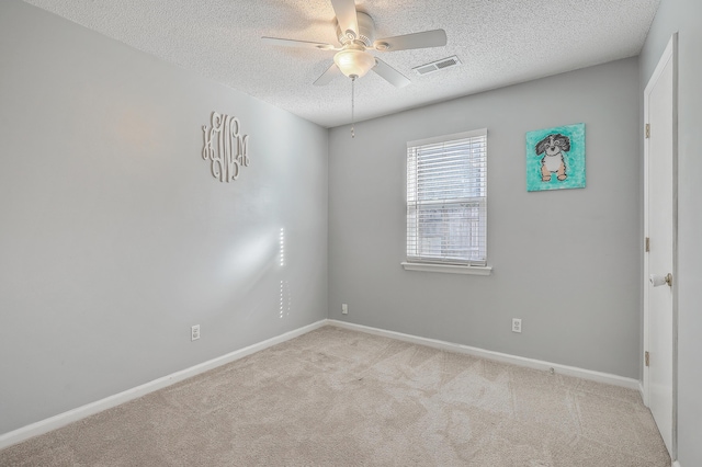 spare room featuring a textured ceiling, light colored carpet, and ceiling fan