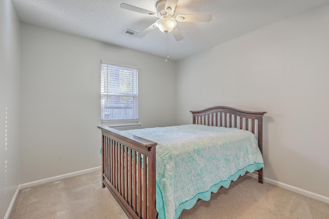 bedroom featuring ceiling fan, light colored carpet, and a textured ceiling