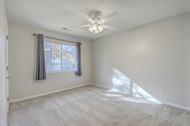 empty room with a textured ceiling, ceiling fan, and light carpet