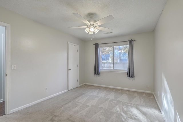 carpeted spare room featuring ceiling fan and a textured ceiling