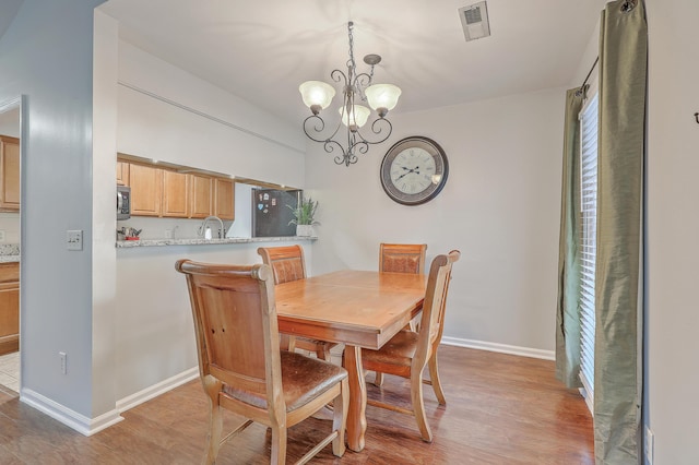 dining room featuring a chandelier, sink, and light hardwood / wood-style flooring