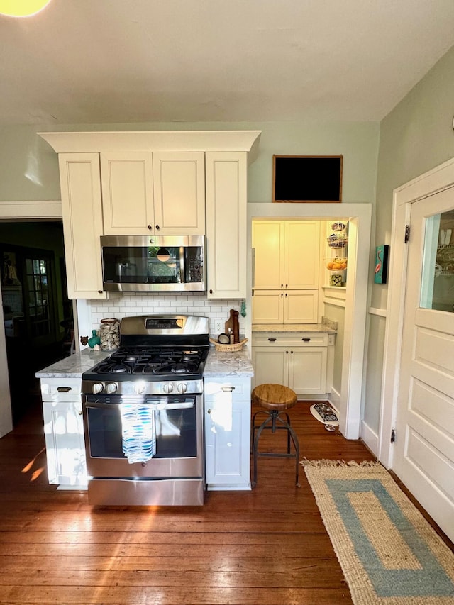 2066 Wappoo Dr, Charleston, SC 29412 - kitchen featuring appliances with stainless steel finishes, decorative backsplash, dark wood-type flooring, and light stone counters