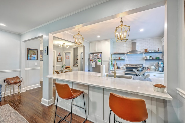 1188 Camden St, North Charleston, SC 29405 - kitchen featuring wall chimney range hood, appliances with stainless steel finishes, a chandelier, dark wood-style flooring, and a kitchen bar