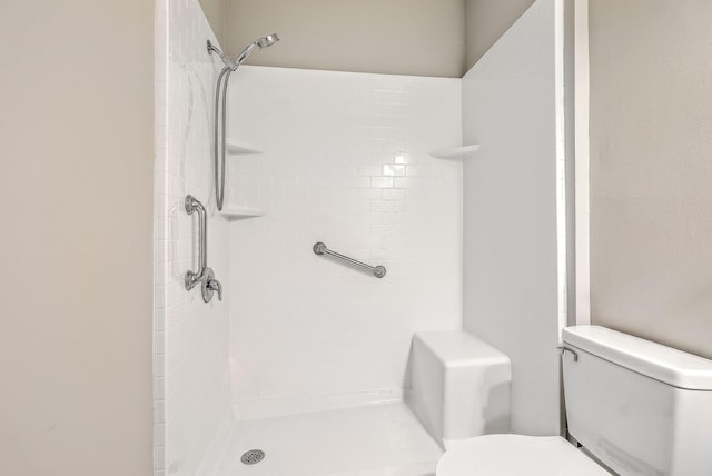 bathroom with a tile shower and toilet