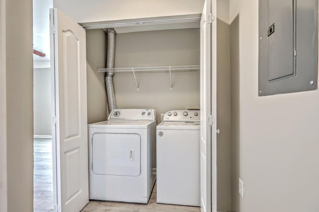 laundry room featuring independent washer and dryer, electric panel, and light hardwood / wood-style flooring