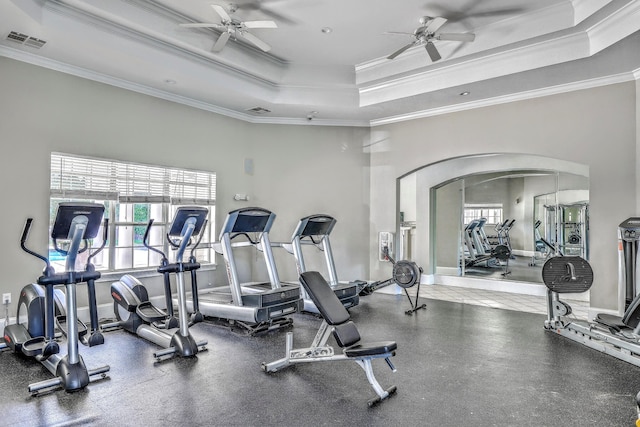 gym with a raised ceiling, ornamental molding, and ceiling fan