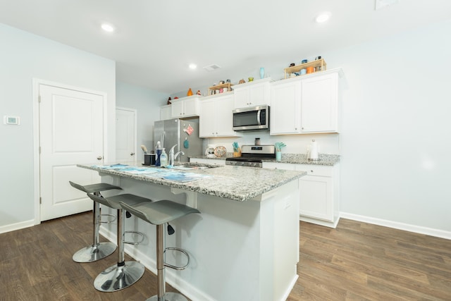 kitchen with white cabinetry, a kitchen island with sink, dark hardwood / wood-style flooring, and appliances with stainless steel finishes