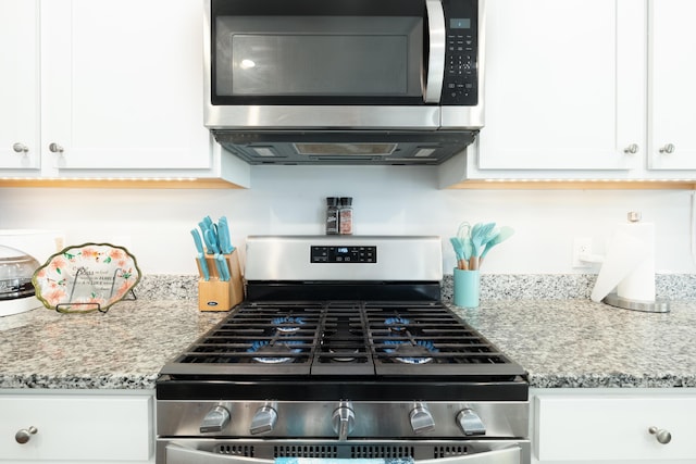 kitchen featuring light stone countertops, stainless steel appliances, and white cabinetry