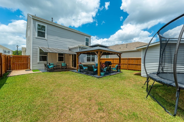 rear view of property featuring a lawn, outdoor lounge area, a trampoline, a gazebo, and a patio area