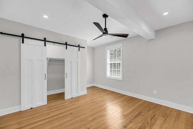 31 Lyttleton St, Charleston, SC 29407 - unfurnished bedroom featuring a barn door, light wood-style flooring, baseboards, a ceiling fan, and a spacious closet