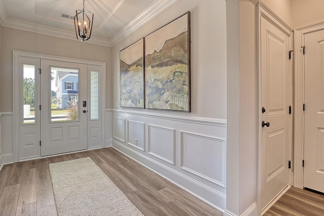 foyer with crown molding, light hardwood / wood-style flooring, and a notable chandelier