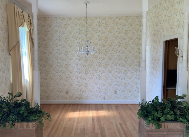 unfurnished dining area featuring wallpapered walls, baseboards, and wood finished floors