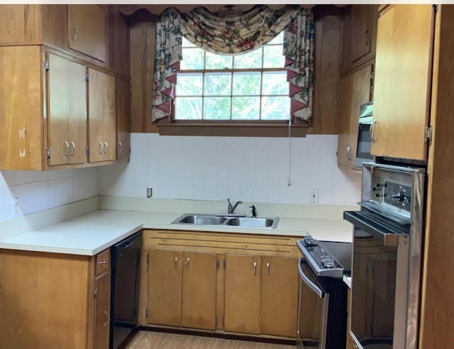 kitchen featuring appliances with stainless steel finishes, brown cabinets, a sink, light countertops, and backsplash