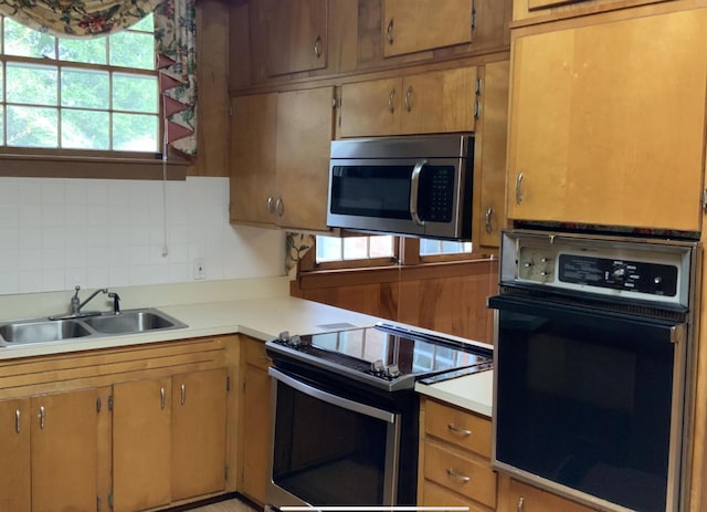 kitchen featuring electric range, a sink, black oven, light countertops, and stainless steel microwave