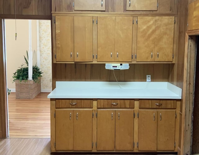 kitchen featuring light wood-type flooring, brown cabinetry, baseboards, and light countertops