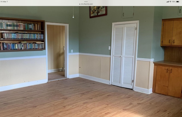 unfurnished dining area featuring a wainscoted wall and light wood-type flooring