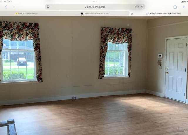 spare room with wood finished floors, a wealth of natural light, and baseboards