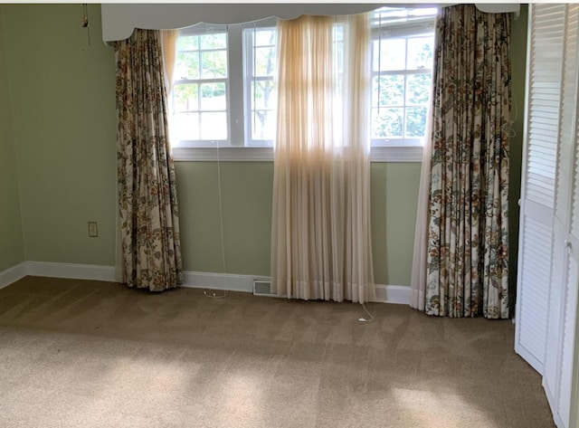 unfurnished room featuring plenty of natural light, carpet, visible vents, and baseboards