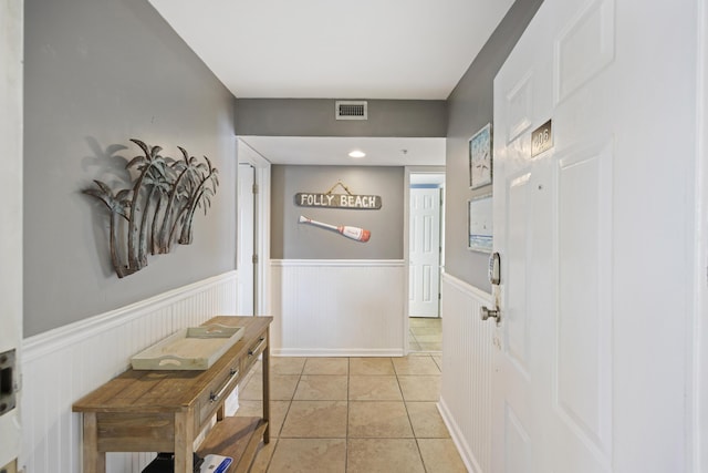corridor featuring wainscoting and light tile patterned floors