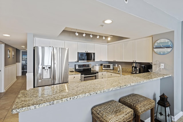 kitchen with appliances with stainless steel finishes, a peninsula, light stone countertops, light tile patterned floors, and recessed lighting
