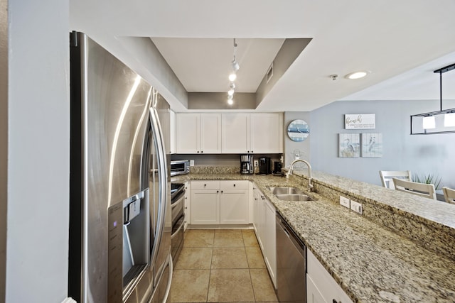kitchen featuring appliances with stainless steel finishes, a sink, white cabinetry, light stone countertops, and track lighting