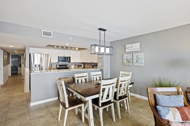 dining space featuring light tile patterned floors and baseboards