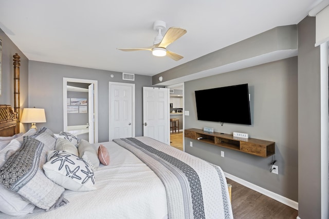 bedroom featuring wood finished floors, baseboards, ceiling fan, and ensuite bathroom