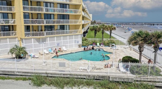 community pool featuring fence, a patio, and a water view