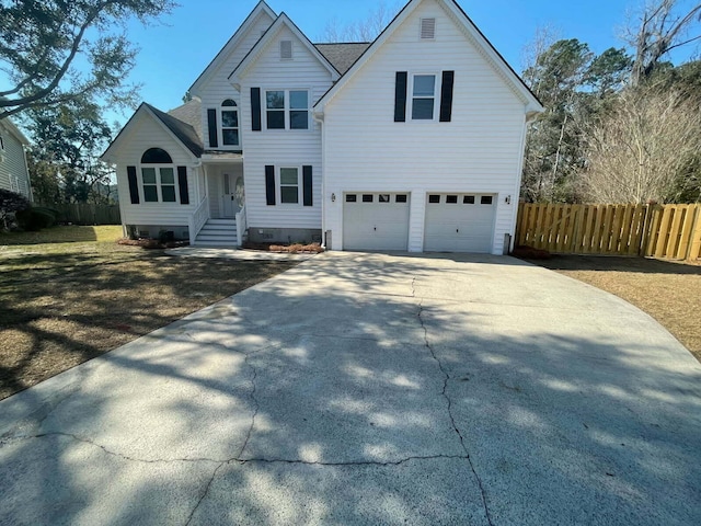 traditional-style house featuring concrete driveway, fence, a garage, and roof with shingles