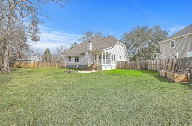 rear view of house with a shingled roof, a sunroom, a fenced backyard, a yard, and crawl space